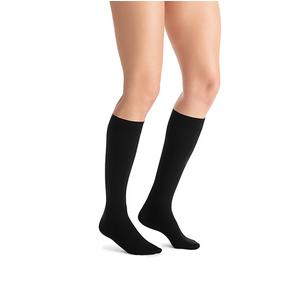 Person wearing black knee-high compression socks on a white background