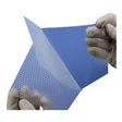 Hands with gloves holding a medical wound dressing with a perforated design