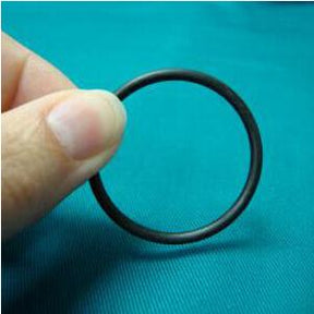 Hand holding black rubber o-ring gasket on teal background, medical supply accessory