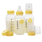 Set of Medela baby bottles with yellow lids and measurement markings, filled with milk