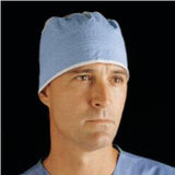 Male healthcare professional wearing blue surgical cap and scrubs, black background