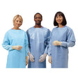 Three people wearing disposable medical isolation gowns and gloves, standing together.