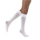 White knee-high medical compression socks on person's legs against white background