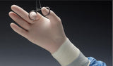Gloved hand in medical gown holding surgical scissors, sterile medical supplies