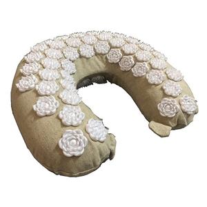 Beige acupressure neck pillow with white lotus-shaped massage spikes