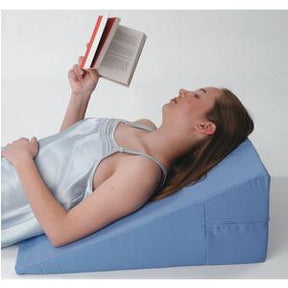 Woman reclining on blue wedge pillow while reading, supportive medical positioning cushion