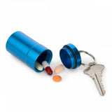 Blue pill holder keychain open with pills and a key on a white background.