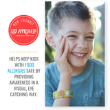 Smiling boy wearing a colorful multi-food allergy awareness bracelet on his wrist.