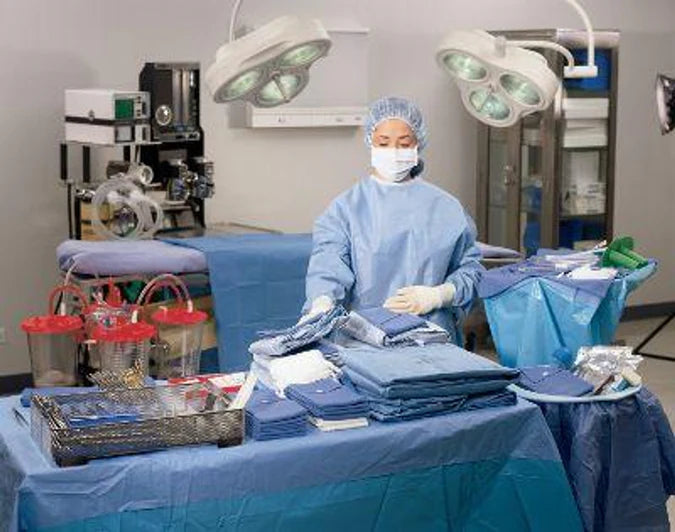 Surgical technician in blue scrubs organizing medical supplies in a hospital operating room.