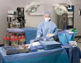 Surgical technician in blue scrubs organizing medical supplies in a hospital operating room.