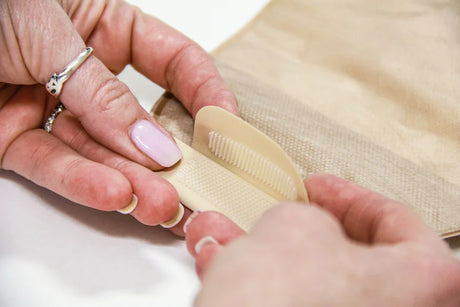 Close-up of hands fastening a beige ostomy pouch closure for medical use