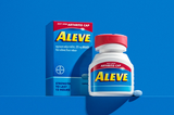 Aleve arthritis cap pain relief tablets with bottle, box and pill on blue background