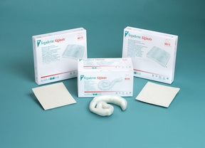 Tegaderm Alginate wound dressings with packaging and medical pads on blue background