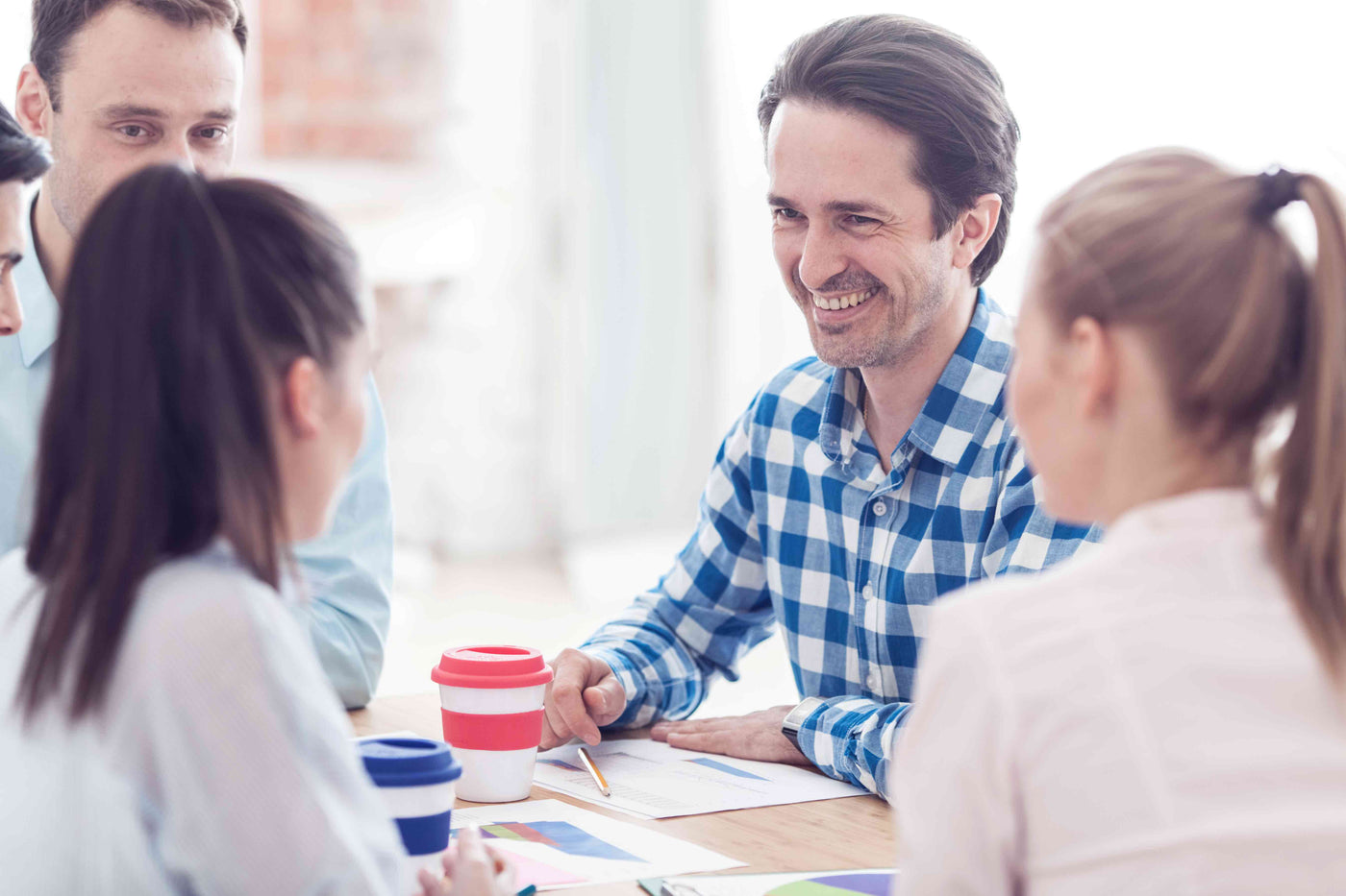Smiling advisor meeting with team around table, discussing documents and charts