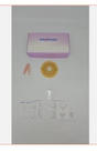 Ostomy care kit with barrier ring, wafer, clips, and adhesive strips on a white background.