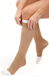 Person putting on beige knee-high compression socks with white toes for medical support