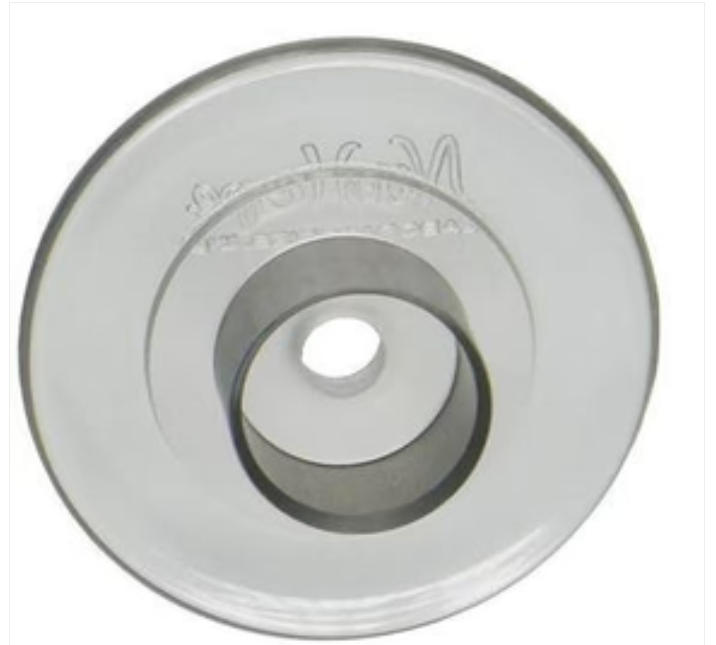 Close-up of a round medical supply part with central hole, metallic finish
