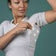 Woman applying adhesive medical patch to upper arm, home medical supply product