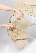 Person applying beige medical compression garment on leg and foot for lymphedema care