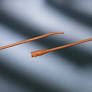 Two orange latex Foley catheters on a soft, blurred background, medical supplies