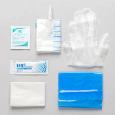 Disposable medical supply kit with gloves, alcohol pad, gauze, and sanitary wipes on gray background