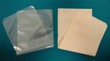 Medical adhesive hydrocolloid wound dressing and clear protective cover on teal background