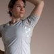 Woman in a light grey medical shirt, posing indoors, representing health and wellness
