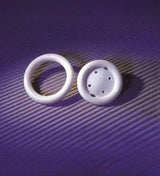 Two white medical rings on a purple surface, one solid with holes, for medical supply use