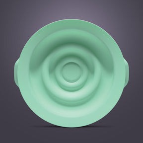 Green silicone breast pump seal with concentric ring design on a neutral background