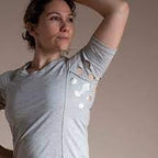 Woman wearing adaptive medical shirt with snap openings on the sleeve, light background
