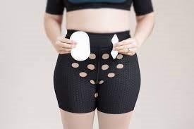 Woman wearing ostomy support underwear and holding ostomy pouch and wafer