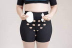 Woman wearing ostomy support underwear and holding ostomy pouch and wafer