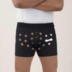Man wearing black ventilated medical underwear with circular cutouts, standing arms crossed