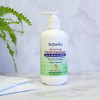 Moisturizing hand sanitizer bottle with pump on marble surface, next to face mask and fern
