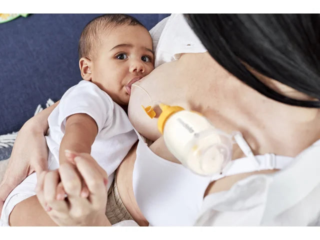 Mother breastfeeding baby with supplemental nursing system and feeding tube