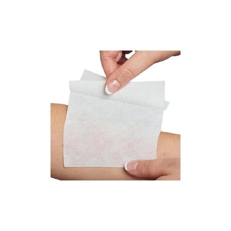 Person applying a sterile medical wound dressing pad to forearm