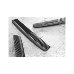 Black plastic hair combs for personal grooming on a light textured surface