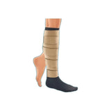 Lower leg wearing adjustable beige compression wrap and black sock for edema management