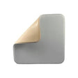Square medical foam dressing with corner peeled back, showing adhesive wound pad