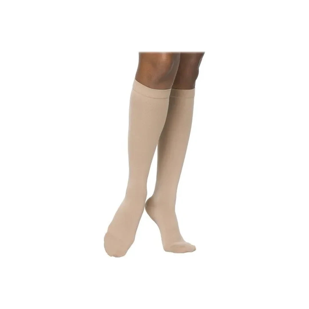 Beige knee-high compression socks for medical support on legs, side view