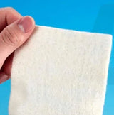 Hand holding a soft white medical gauze pad against a blue background
