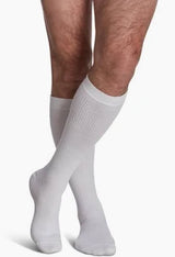 Person wearing white knee-high compression socks for medical support on legs