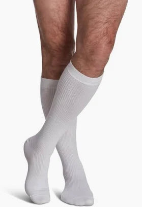 Person wearing white knee-high compression socks for medical support on legs