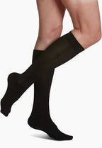 Person wearing knee-high black compression socks on bare legs