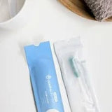 Individually packaged toothbrush and dental care kit on white surface