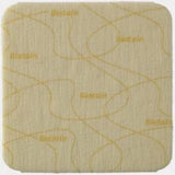 Square beige medical adhesive dressing with curved edges and printed pattern