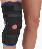 Person wearing an adjustable black knee brace for joint support and injury recovery