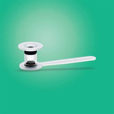 Clear plastic medical device with a flat circular base and extended handle on green background