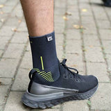 Person wearing a black compression sock and athletic shoe on a paved walkway