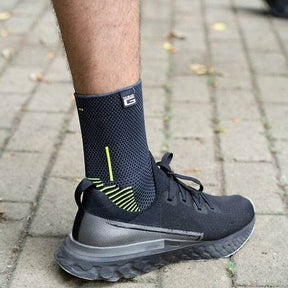 Person wearing a black compression sock and athletic shoe on a paved walkway